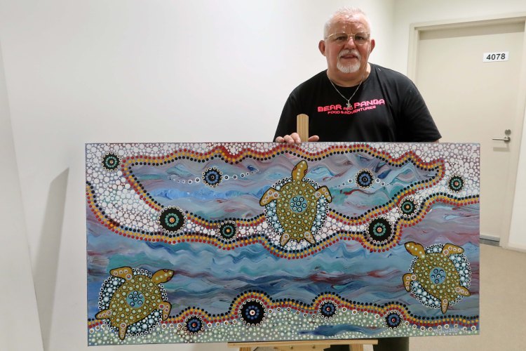 Robb Wang standing behind a turtle painting
